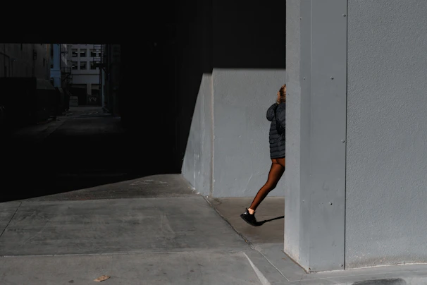 Full-body shot of a model wearing eclipse tailored joggers walking through a dimly lit urban alley at night.
