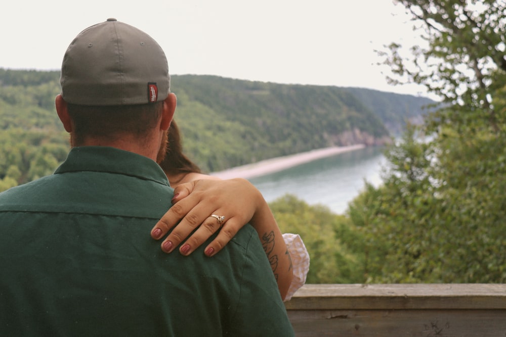 a man and a woman sitting on a bench looking at a lake