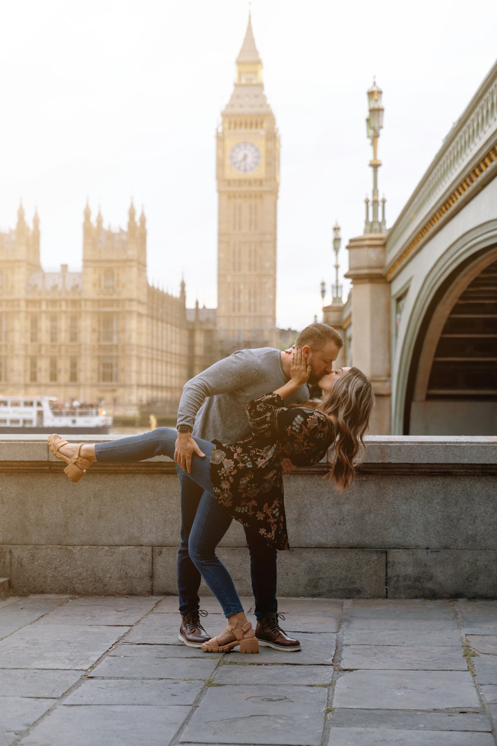 um homem e uma mulher se beijando na frente de uma torre do relógio