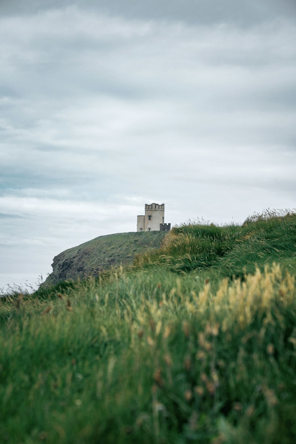 a small white building on a grassy hill