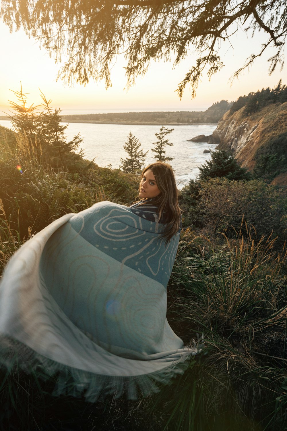 a woman in a blue and white dress sitting in the grass