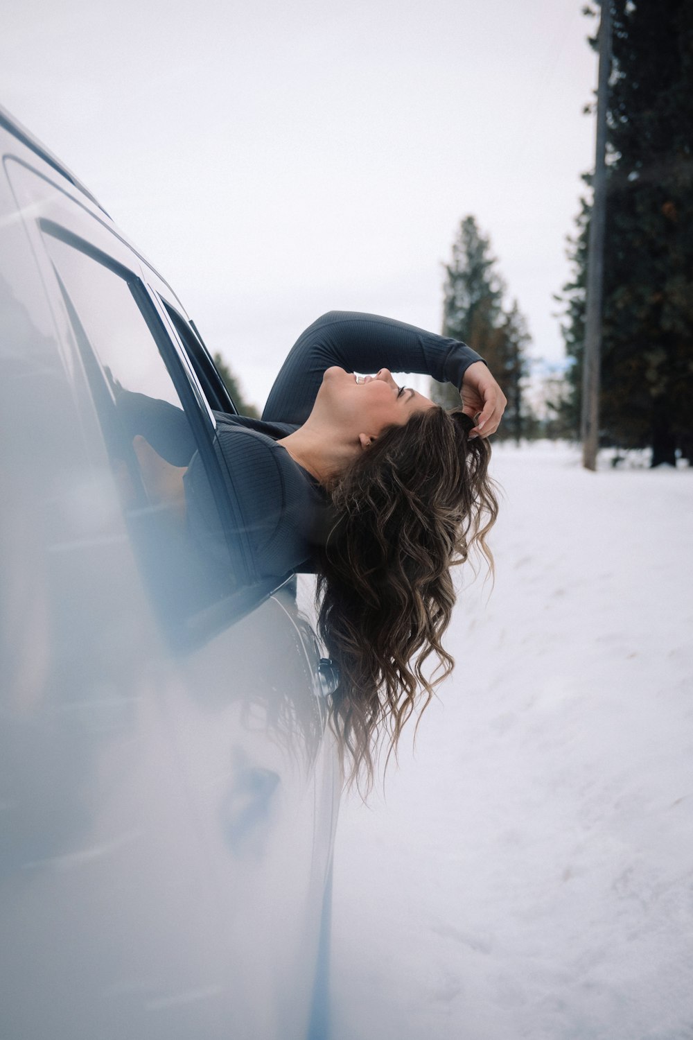 uma mulher inclinada para fora da janela de um carro na neve