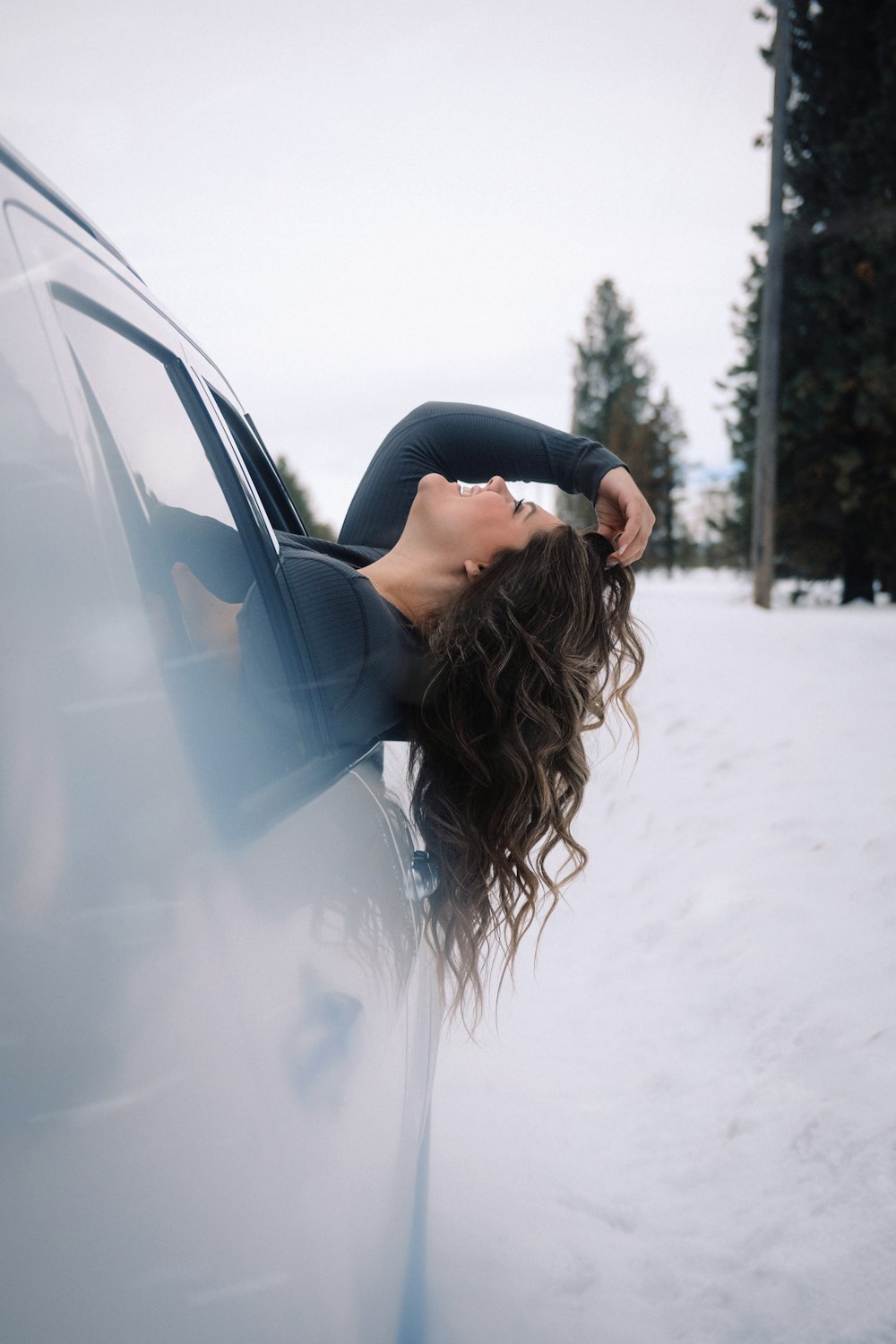 雪の中で車の窓から身を乗り出す女性