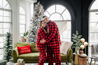 a man and a woman in pajamas standing in front of a christmas tree