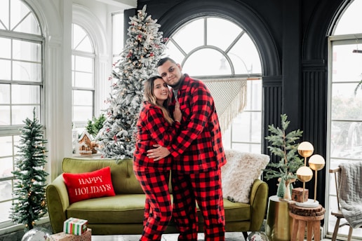 a man and a woman in pajamas standing in front of a christmas tree