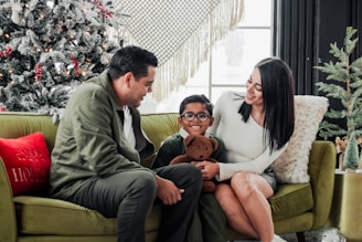 a family sitting on a couch in front of a christmas tree