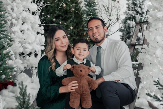 A family happily choosing a Christmas tree together in a festive outdoor lot.