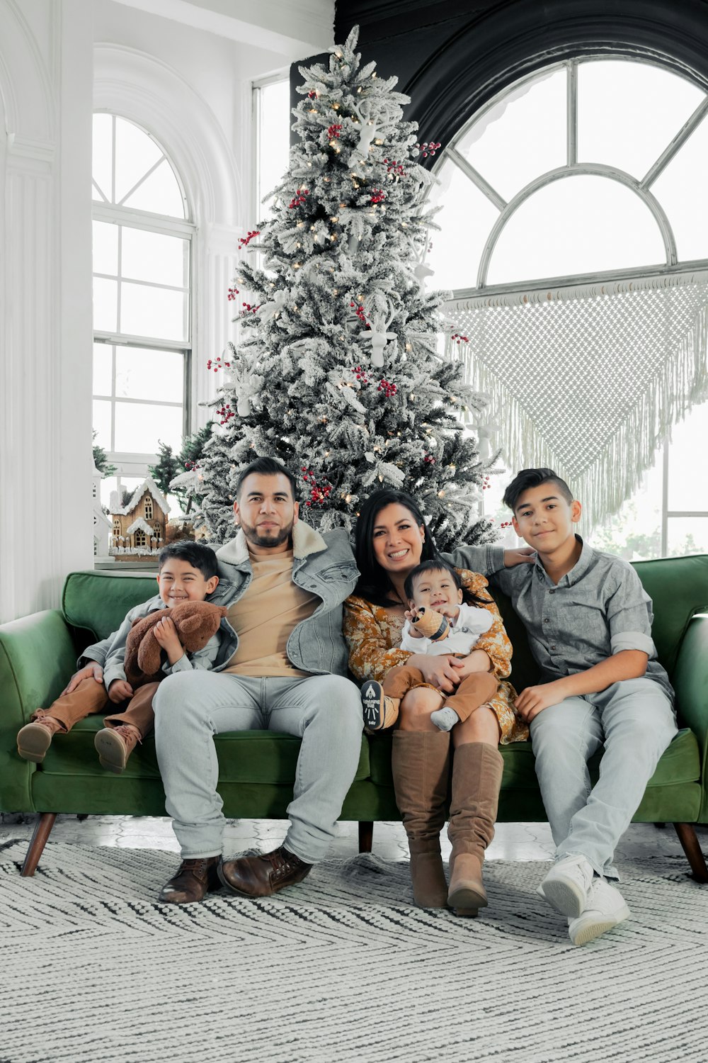 a family sitting on a couch in front of a christmas tree
