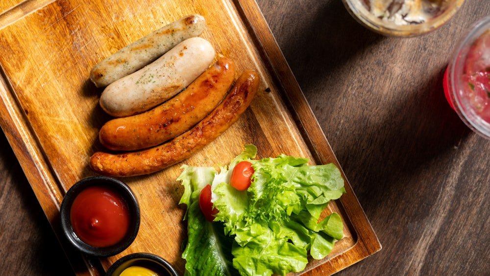 a wooden tray topped with hot dogs and vegetables