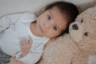 A friendly baby with a soft toy in a cozy nursery setting.