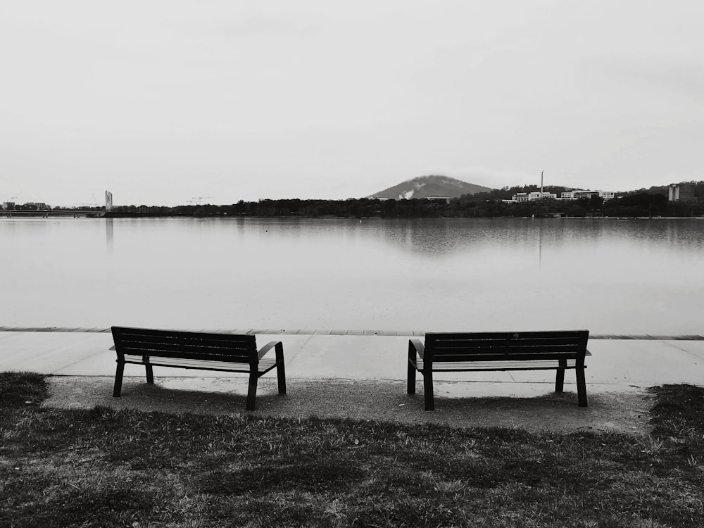 a couple of benches sitting next to a lake