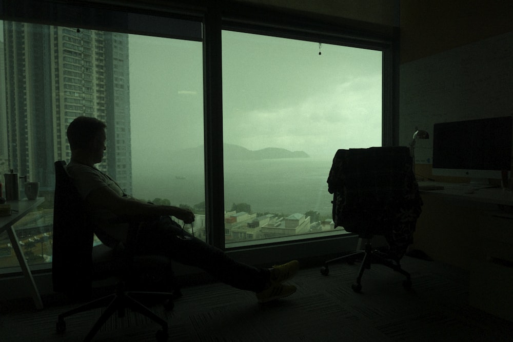 a man sitting in a chair in front of a window