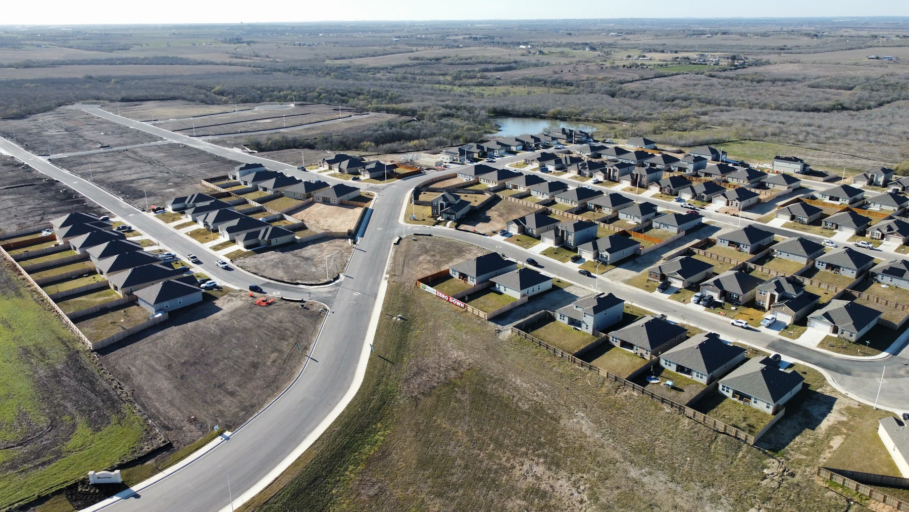 Pogled na stanovanjsko območje z urejeno cestno mrežo in zelenimi površinami.