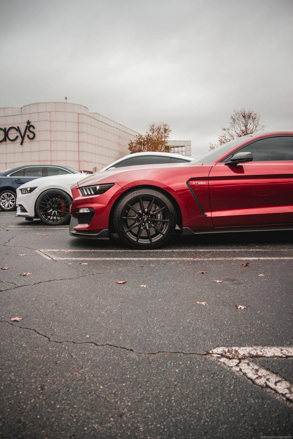 a red mustang parked in a parking lot