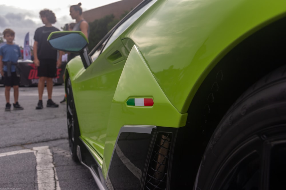 a group of people standing around a green sports car