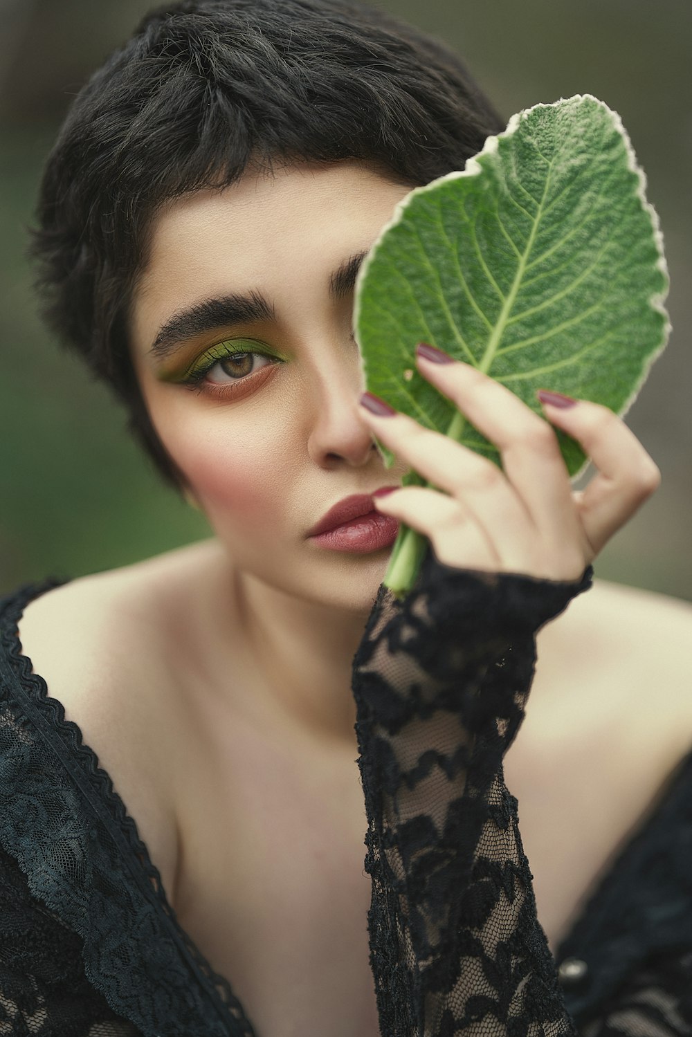 a woman holding a leaf over her face