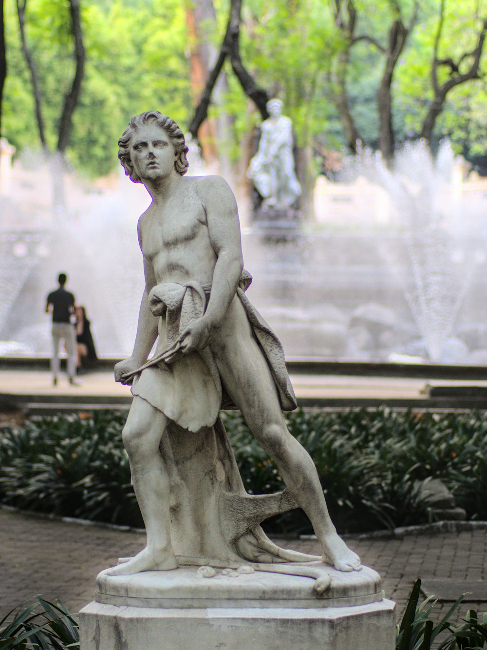 Una estatua de un hombre parado frente a una fuente