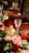 A beautifully set dining table adorned with an arrangement of colorful flowers. Crystal glasses are placed neatly beside elegant brown plates, creating a warm and inviting atmosphere.