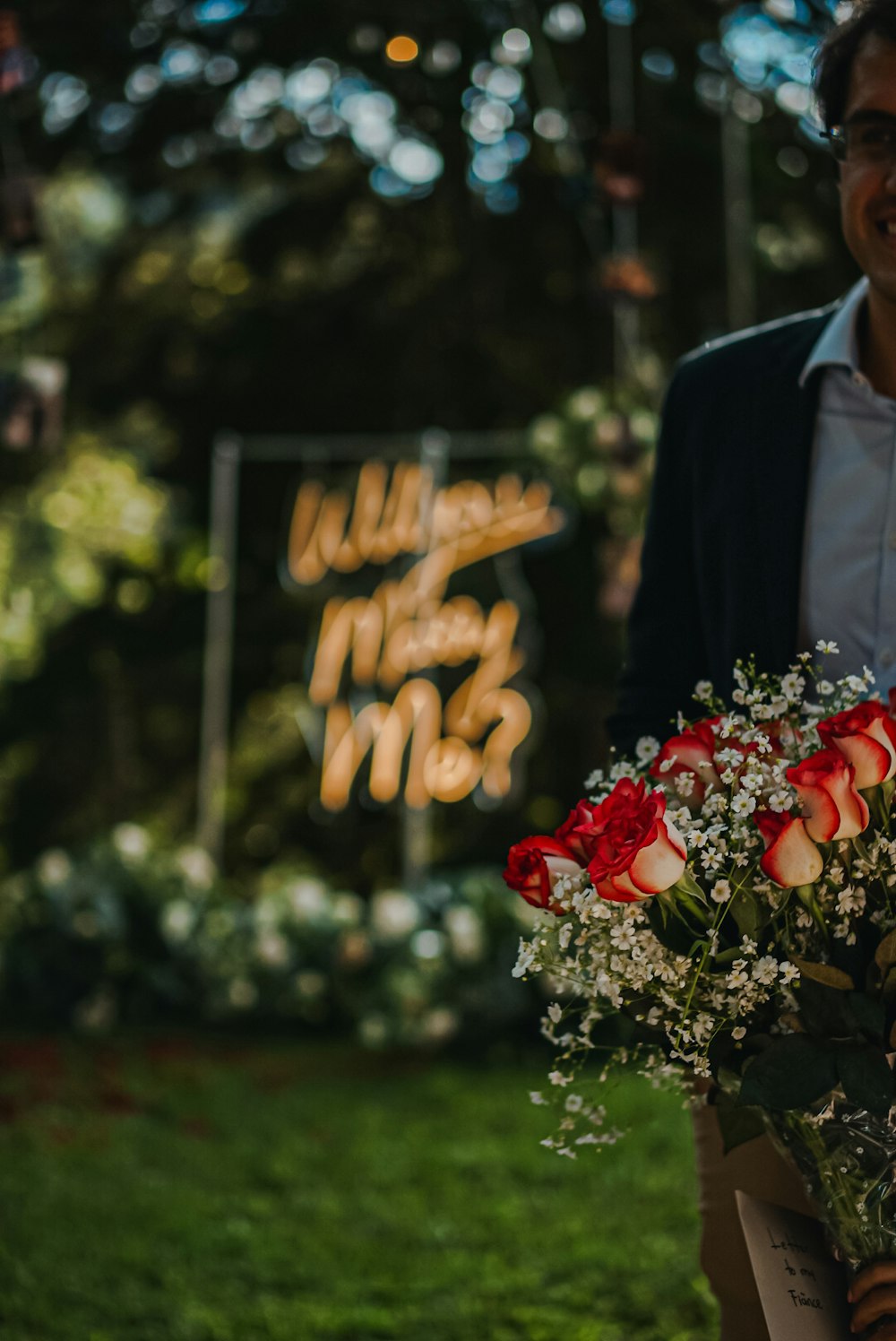 a man holding a bouquet of roses in front of a sign
