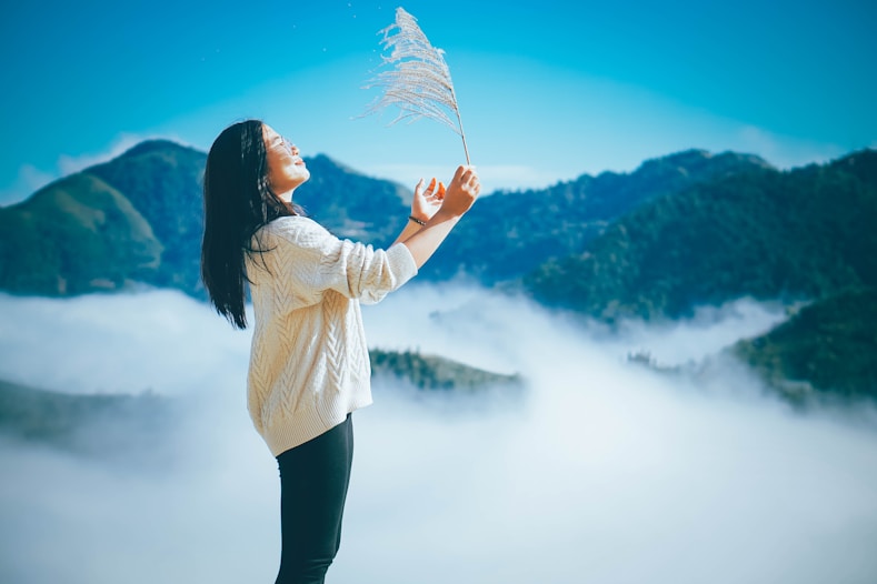 a woman standing on top of a mountain holding a plant