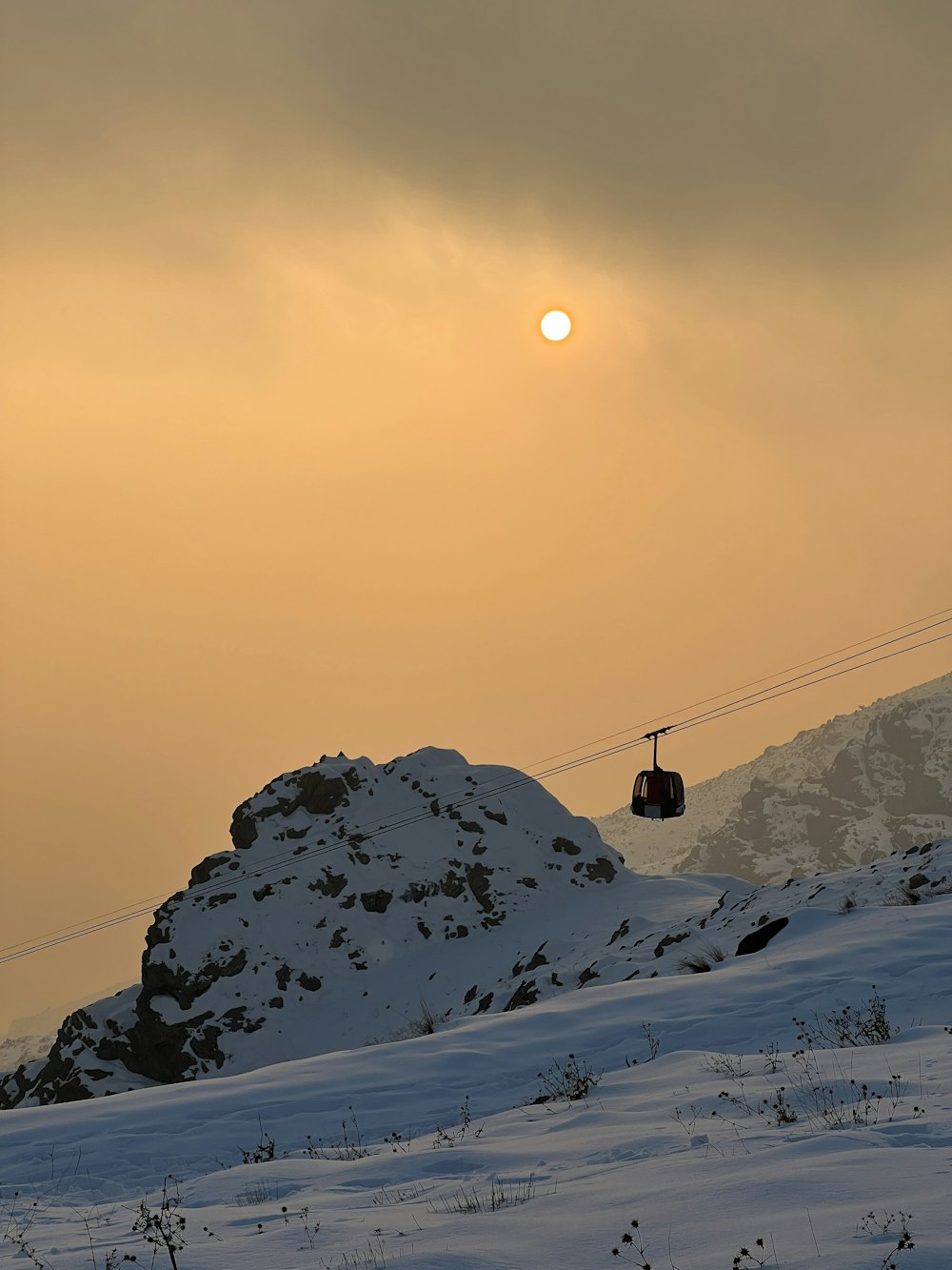 the sun is setting over a snowy mountain