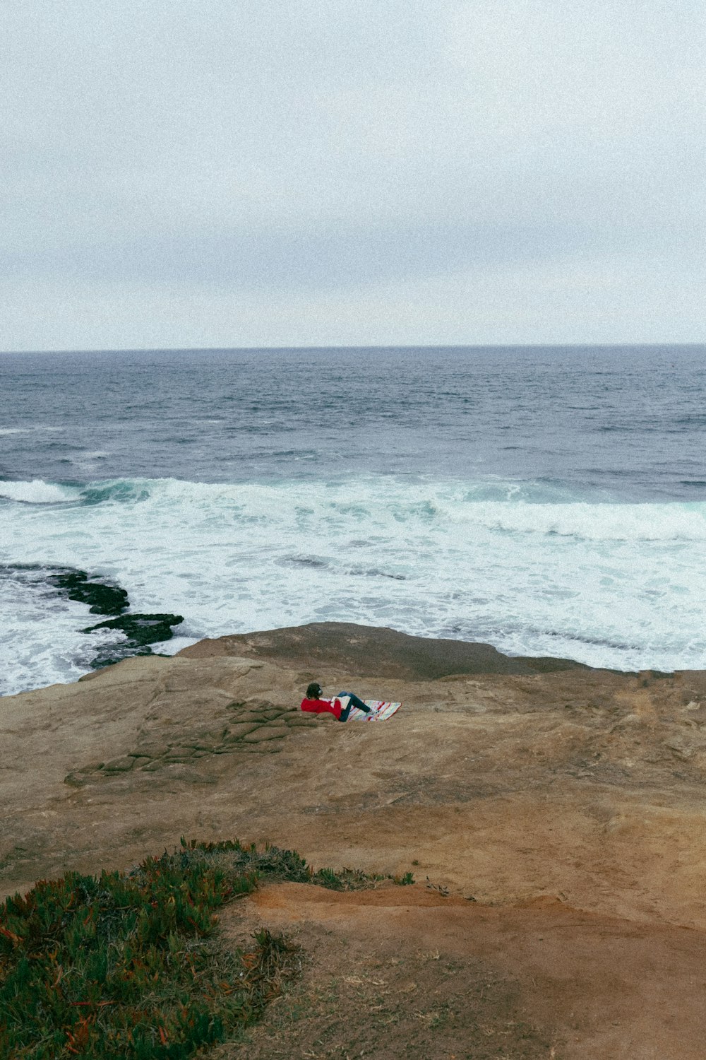 a person laying on top of a beach next to the ocean
