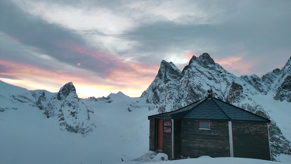 a cabin in the snow with mountains in the background