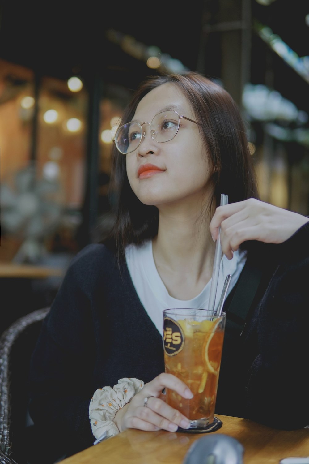 a woman sitting at a table with a drink in her hand