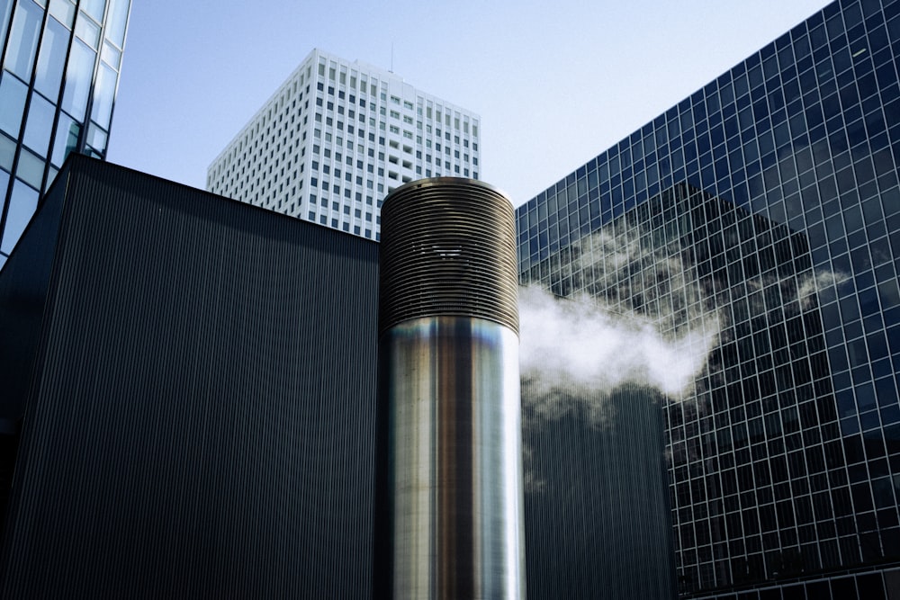 a smokestack in front of a building with skyscrapers in the background