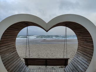 a heart shaped bench sitting on top of a sandy beach