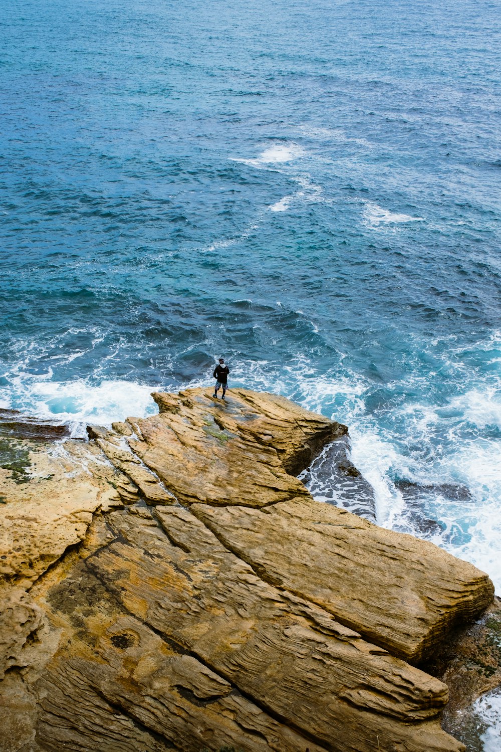 a person standing on top of a cliff near the ocean