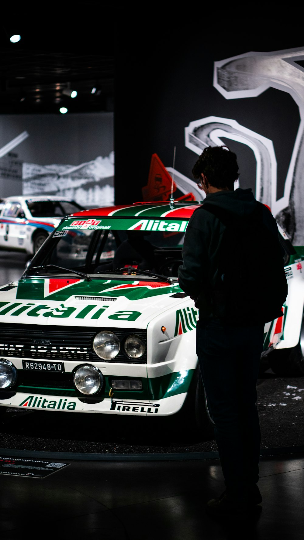 Un uomo in piedi accanto a un'auto in mostra