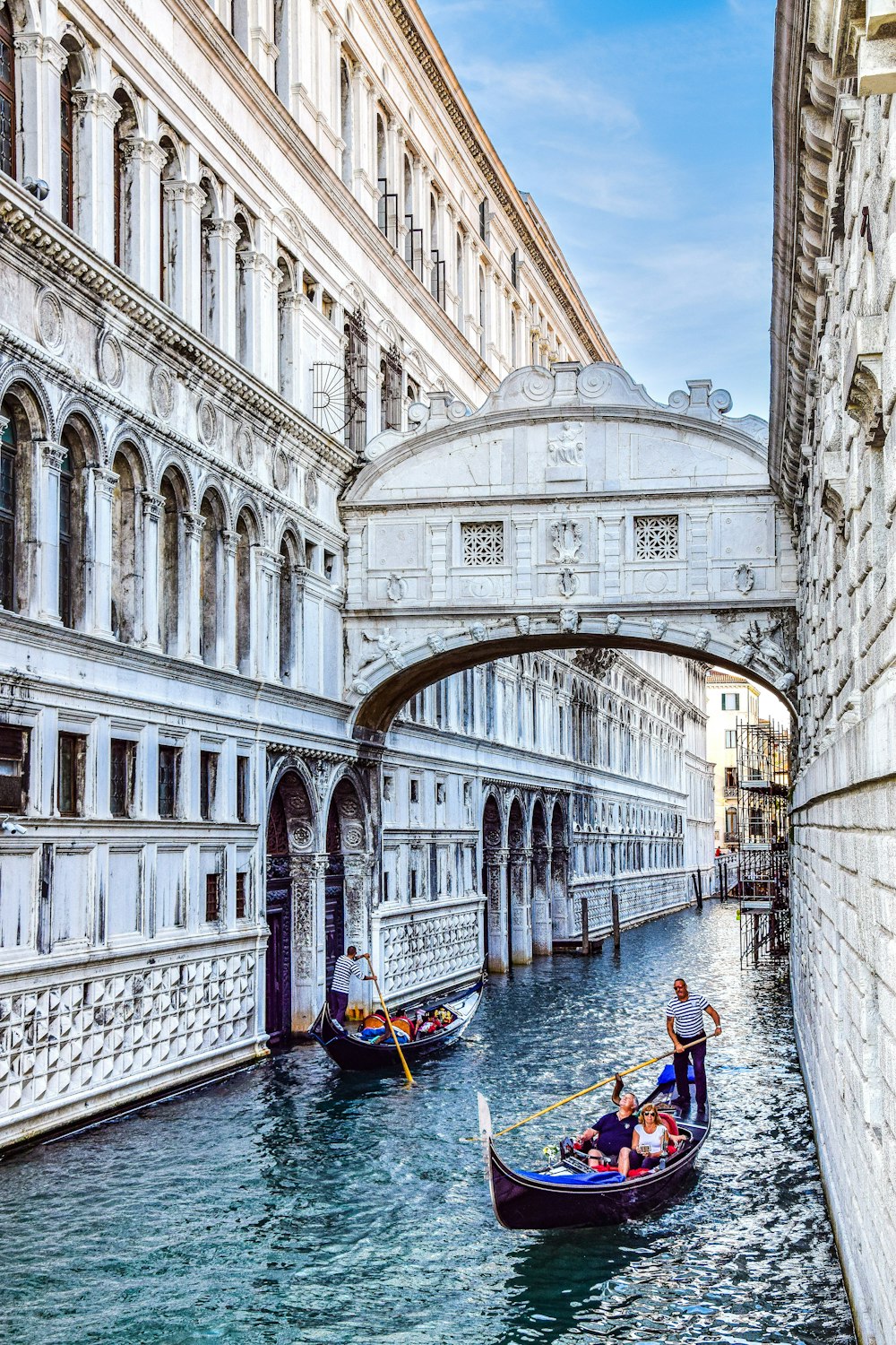 a couple of boats floating down a river under a bridge