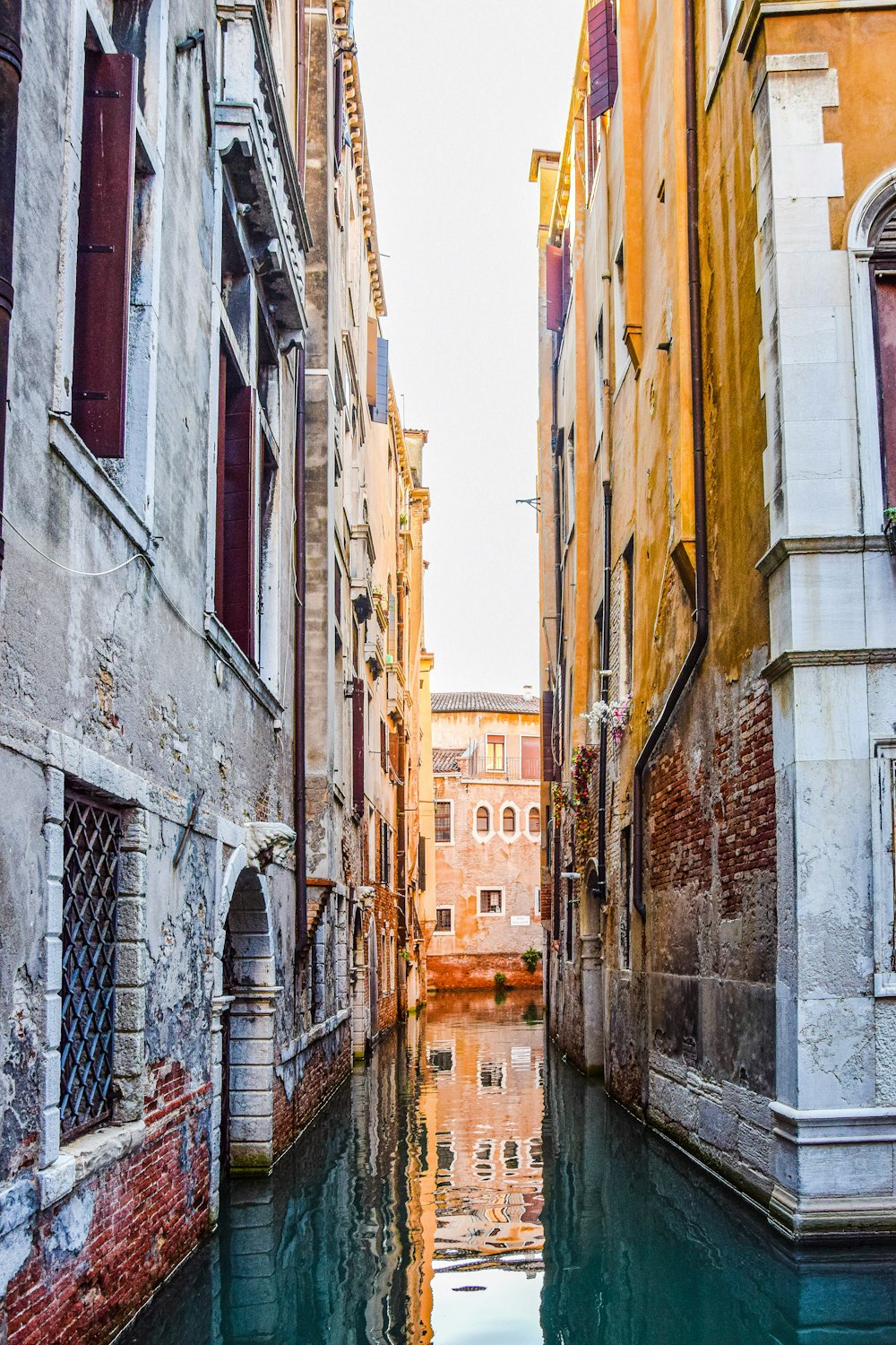 a narrow canal runs between two buildings in venice