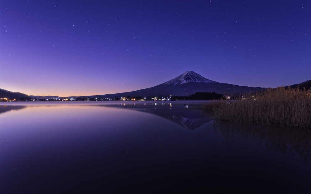a night scene of a lake with a mountain in the background