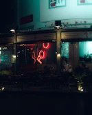 Evening scene of the café’s exterior with subtle neon signage glowing against the dark theme.