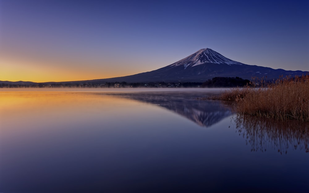 a mountain is in the distance with a lake in front of it