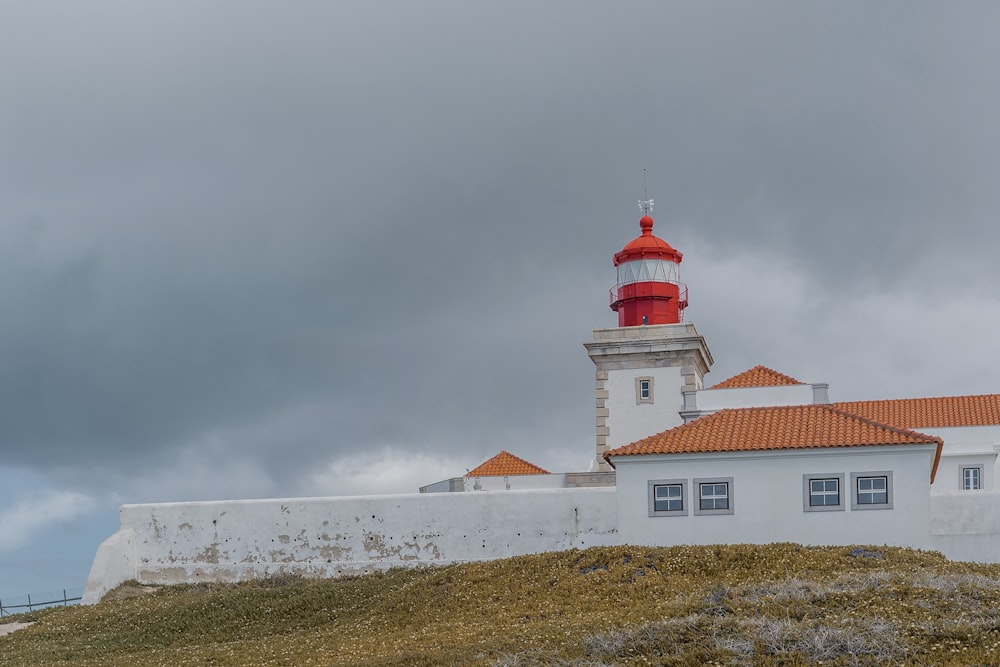 a red and white lighthouse on a cloudy day