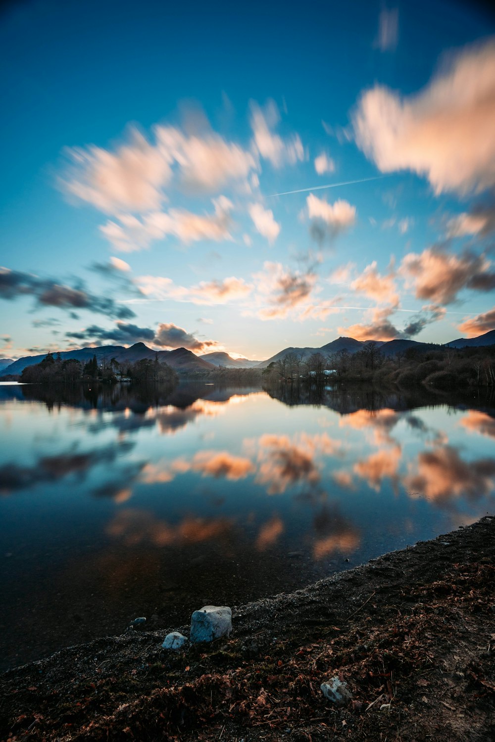 a body of water surrounded by mountains under a cloudy sky