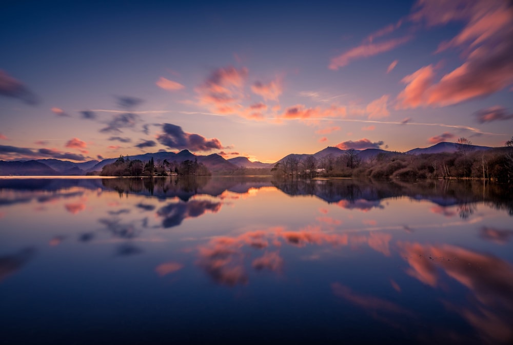 a lake with mountains in the background at sunset