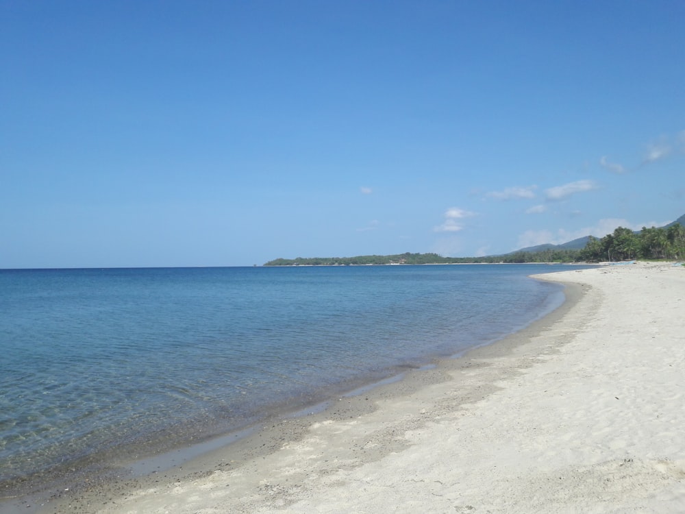 a sandy beach with clear blue water on a sunny day