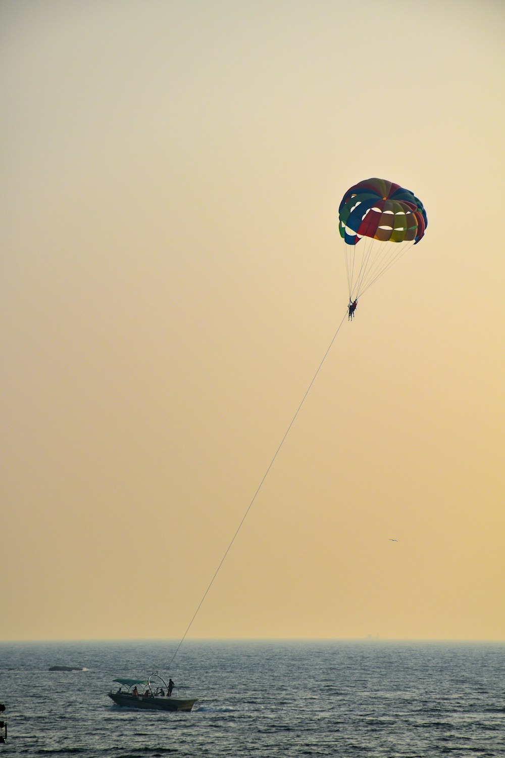 a person parasailing in the ocean with a boat in the background