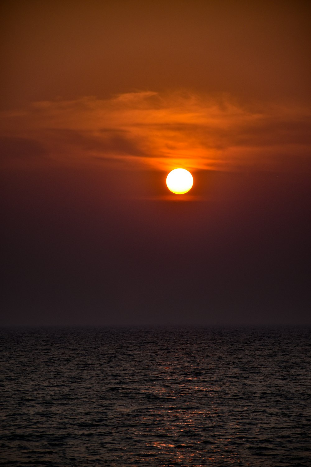 the sun is setting over the ocean on a cloudy day