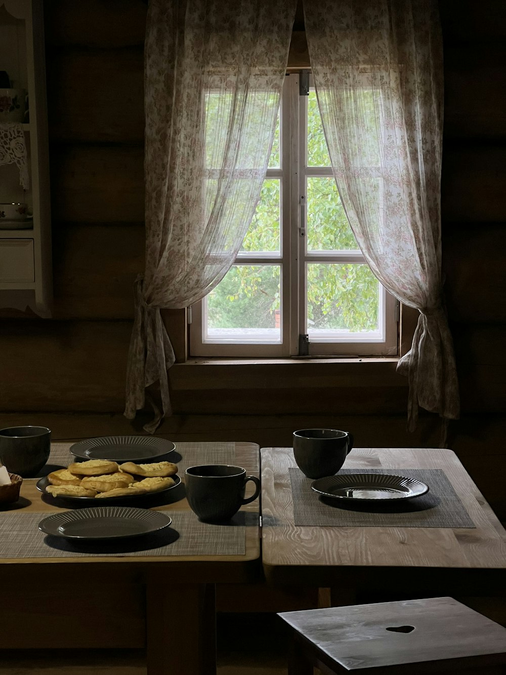 a wooden table topped with plates of food next to a window
