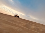 Golden desert dunes at sunset with a luxury 4x4 vehicle in Dubai.