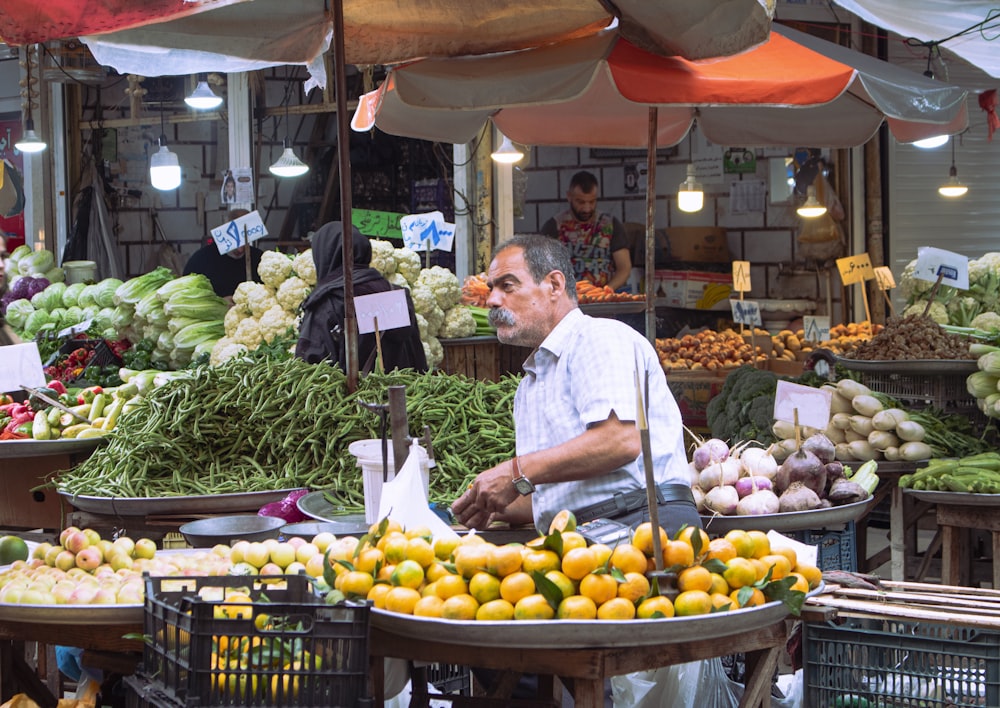 a man standing in front of a fruit and vegetable stand