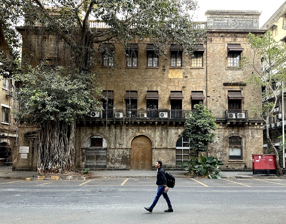 a man walking across a street next to a tall building