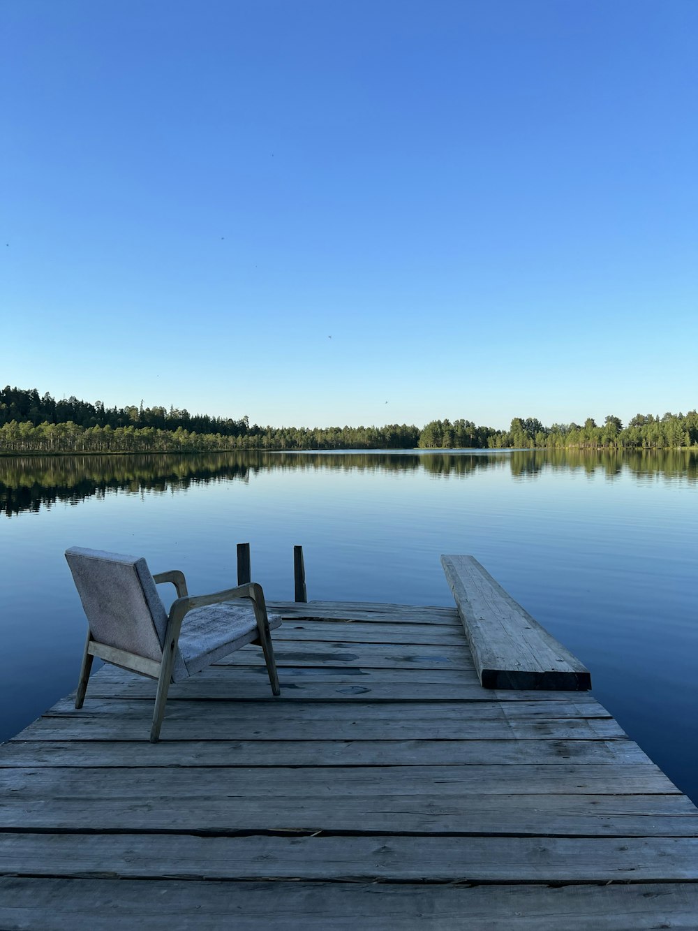 a chair sitting on a dock next to a body of water