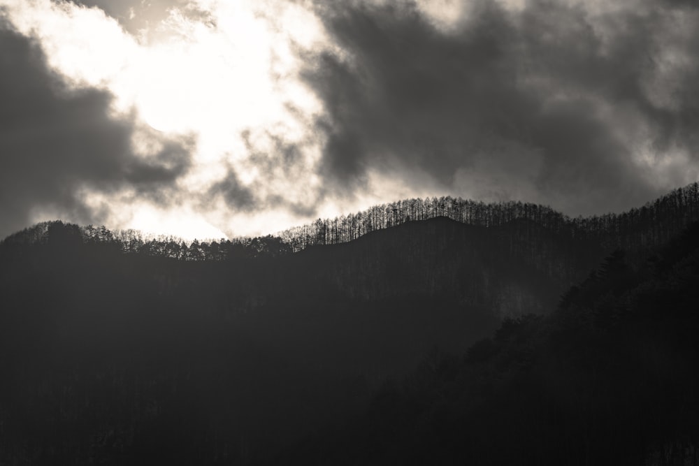 a black and white photo of a mountain with clouds