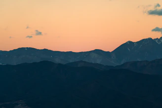 Wide scenic view of a rugged mountain range with soft teal-to-blue gradient sky.